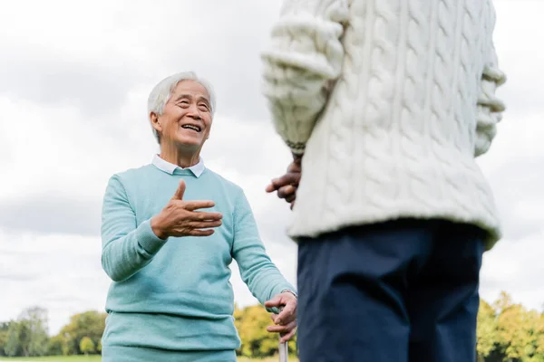 Low angle view of happy senior asian man talking with african american friend — стоковое фото