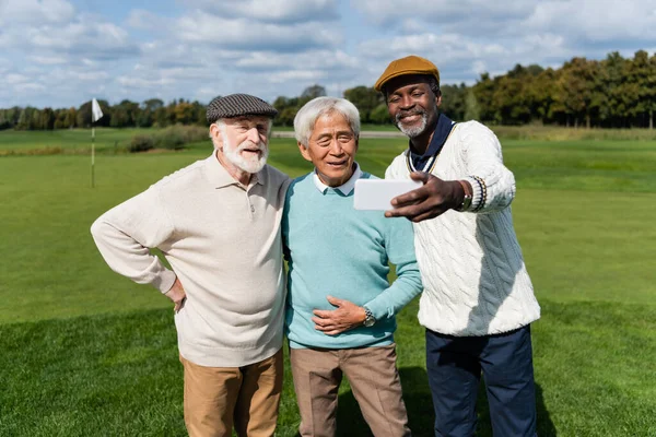 Feliz africano americano hombre tomando selfie con senior interracial amigos - foto de stock