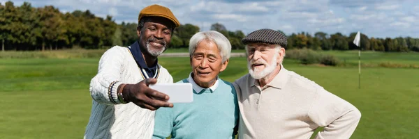 Happy african american man taking selfie with senior interracial friends, banner — Stock Photo