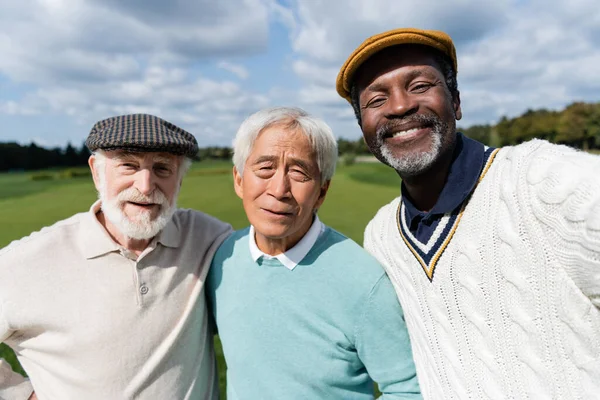 Homem americano africano alegre olhando para a câmera com amigos multiétnicos seniores — Fotografia de Stock