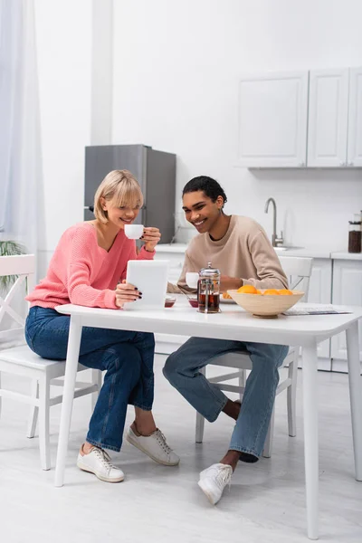 Happy african american man and cheerful woman looking at digital tablet during breakfast — Photo de stock