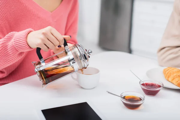 Abgeschnittene Ansicht einer Frau, die Tee in der Nähe von digitalen Tabletten mit leerem Bildschirm gießt — Stock Photo