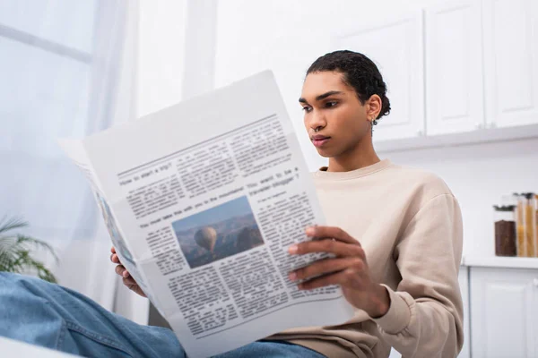 Jeune homme afro-américain en sweat-shirt lecture journal le matin — Photo de stock