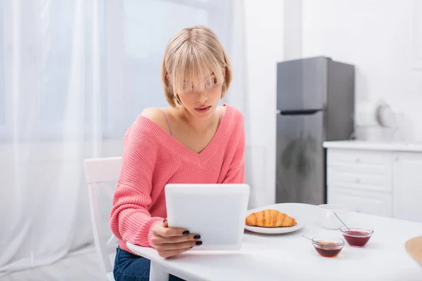 Young blonde woman using digital tablet during breakfast — Fotografia de Stock