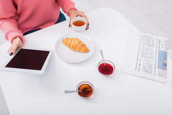 Vue recadrée de la femme tenant tablette numérique avec écran blanc pendant le petit déjeuner — Photo de stock