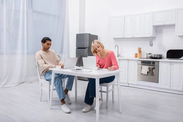 Jeunes pigistes multiethniques travaillant à domicile avec des ordinateurs portables — Photo de stock