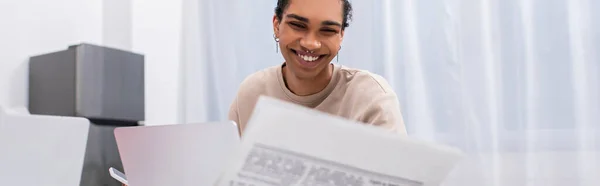 Feliz jovem afro-americano homem ler jornal perto de laptop, banner — Fotografia de Stock