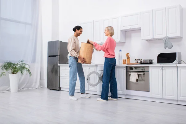 African american man holding basket near washing machine and happy girlfriend — Fotografia de Stock