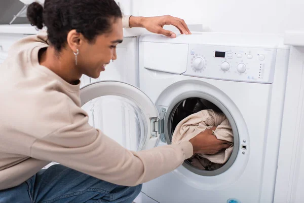 Felice uomo africano americano che mette la lavanderia in lavatrice — Foto stock