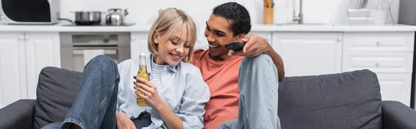 Happy african american man looking at cheerful woman with bottle of beer, banner — Photo de stock