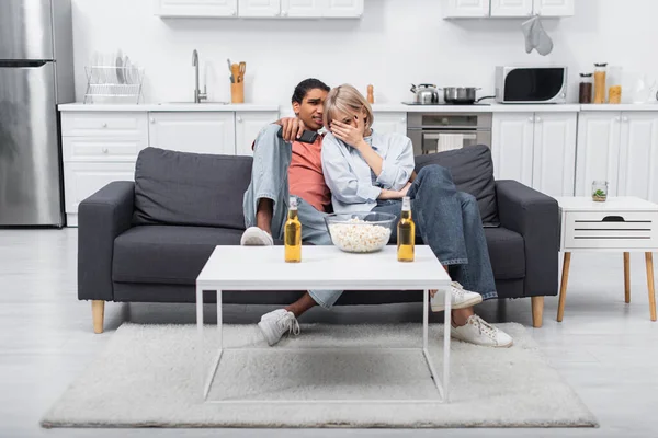 Young interracial couple watching scary movie in living room — Foto stock