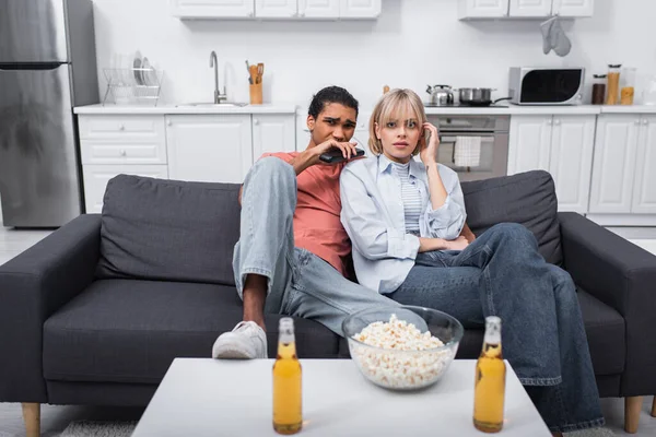 Jovem casal multiétnico assistindo filme assustador na sala de estar — Fotografia de Stock
