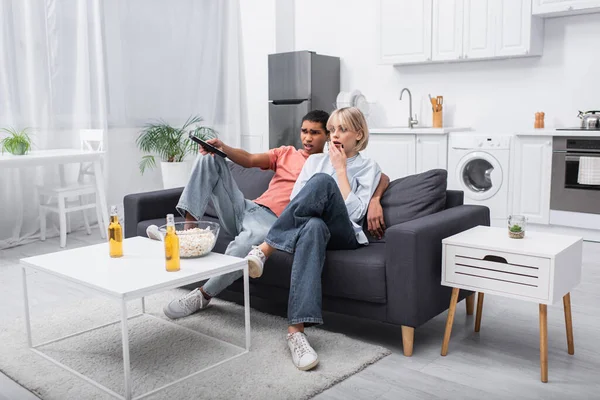 Scared interracial couple watching movie in living room — Fotografia de Stock