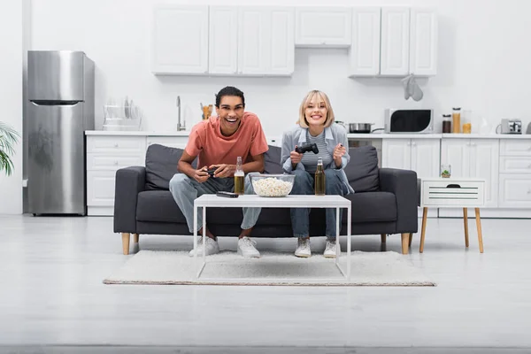 KYIV, UKRAINE - DECEMBER 6, 2021: happy multiethnic couple playing video game in living room — Photo de stock