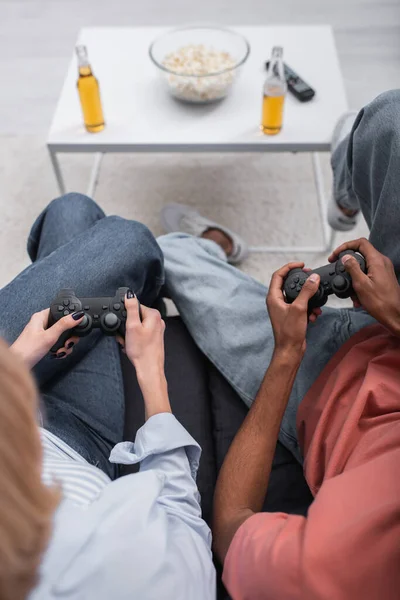 KYIV, UCRANIA - 6 DE DICIEMBRE DE 2021: vista superior de una pareja interracial jugando videojuegos - foto de stock