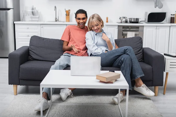 Heureux couple multiethnique souriant pendant l'appel vidéo sur ordinateur portable — Photo de stock