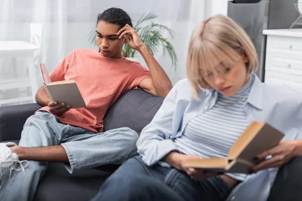 Joven afroamericano hombre y mujer rubia leyendo libros - foto de stock