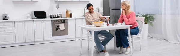 Happy african american man pouring tea near blonde girlfriend, banner — Fotografia de Stock