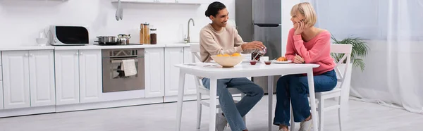 Positif homme afro-américain verser le thé près de petite amie blonde, bannière — Photo de stock