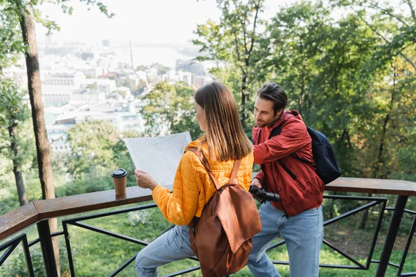 Tourist holding map near boyfriend with binoculars and coffee to go in city — Stock Photo