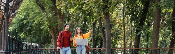 Traveler holding takeaway drink and binoculars near girlfriend with map on urban street, banner — Stock Photo