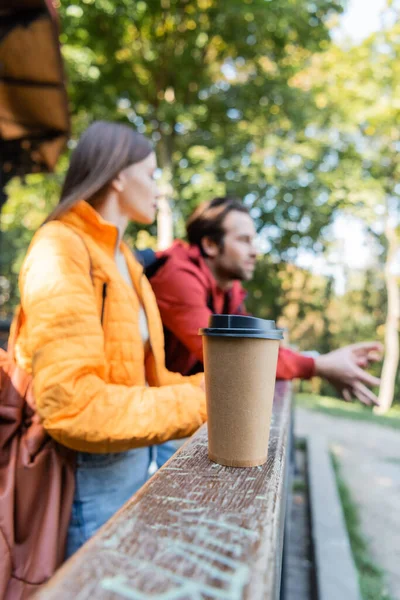 Bebida para llevar cerca de borrosa pareja de turistas al aire libre - foto de stock