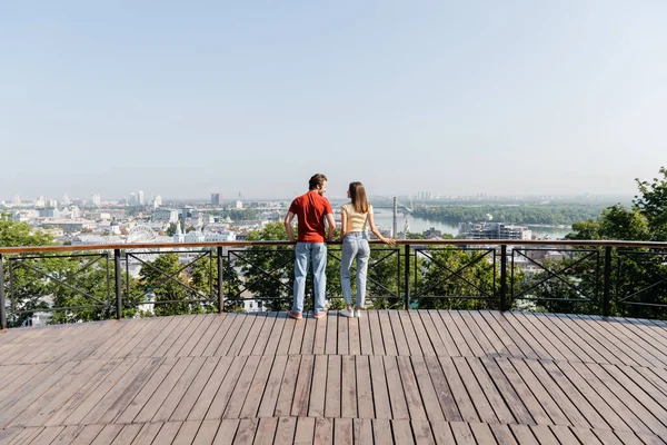 Vista lateral de turistas positivos olhando uns para os outros no ponto de vista na cidade — Fotografia de Stock