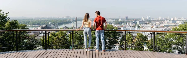 Вид збоку позитивних мандрівників, що стоять біля перил на краєвид міста, банер — стокове фото