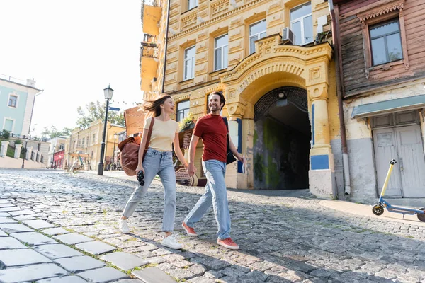 Cheerful tourists with map and binoculars walking on urban street in city — Stock Photo