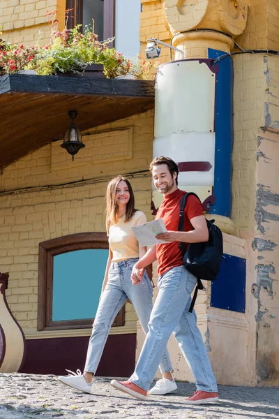 Couple positif avec carte marchant sur la rue urbaine — Photo de stock