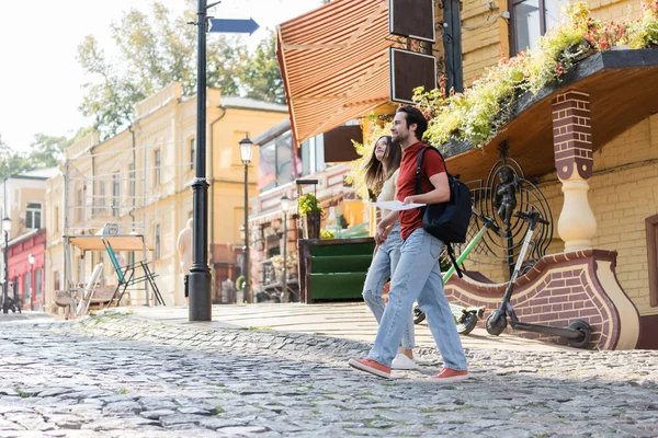 Young travelers with backpack and map walking on urban street — Stock Photo