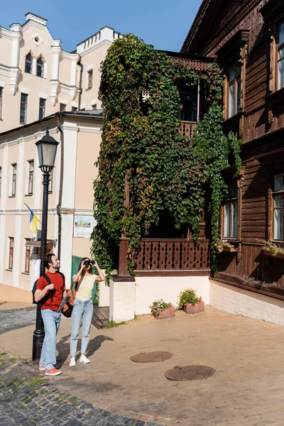 Reisender blickt mit Rucksack und Karte durch Fernglas in der Nähe seines Freundes — Stockfoto