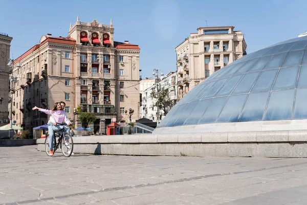 Happy woman riding bike with young boyfriend on urban street — Stock Photo