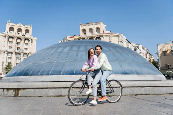 Pareja joven sonriendo mientras pedalea en la calle urbana - foto de stock