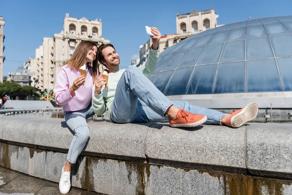 Tourists with ice cream taking selfie on smartphone on urban street — Stock Photo