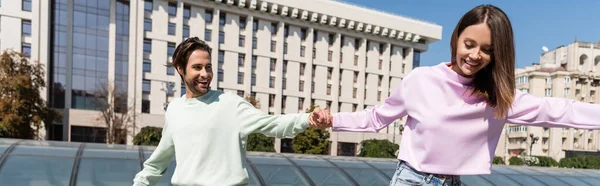 Smiling young couple holding hands on urban street, banner — Stock Photo