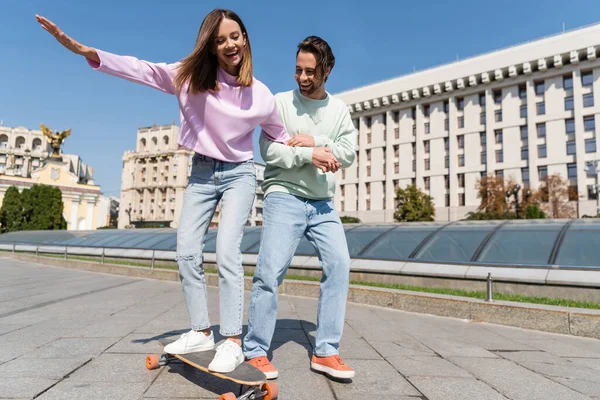 Couple positif équitation penny board sur la rue urbaine — Photo de stock