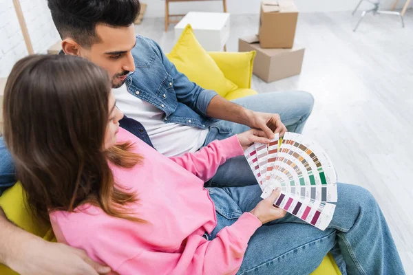 Vue grand angle du couple interracial regardant la palette de couleurs à la maison — Photo de stock