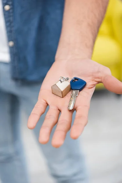 Cropped view of key on hand of blurred man at home — стоковое фото