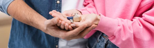 Cropped view of couple holding key at home, banner — Stock Photo