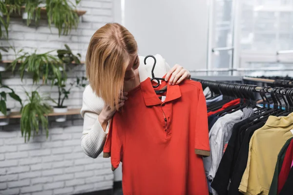 Jeune femme tenant un t-shirt dans un magasin vintage — Photo de stock