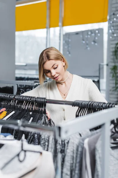 Blonde woman choosing clothes in vintage shop — Foto stock