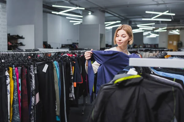 Pretty woman choosing clothes in second hand — Stock Photo
