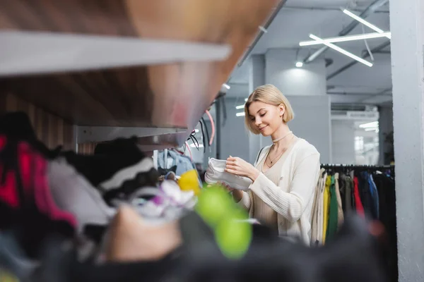 Femme souriante tenant chaussure d'occasion — Photo de stock