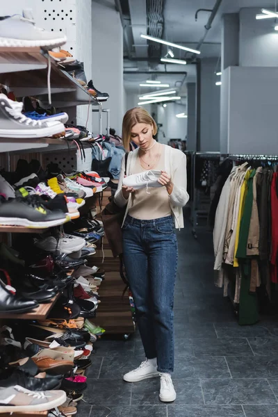 Young woman holding shoe near footwear in vintage shop — Stock Photo