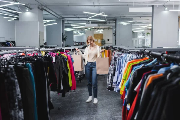 Femme souriante tenant des sacs à provisions d'occasion — Photo de stock