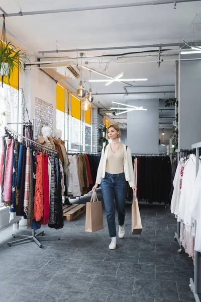 Femme tenant des sacs à provisions tout en marchant dans une seconde main — Photo de stock