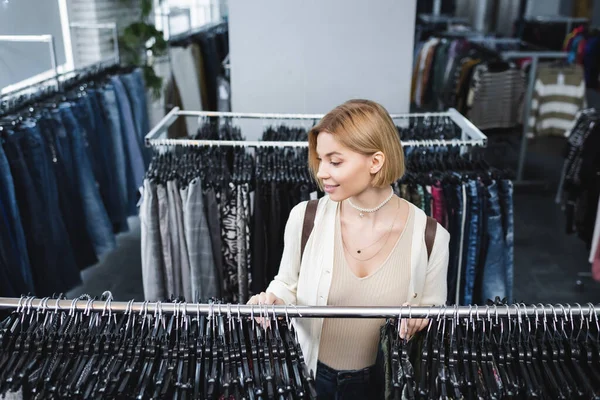 Высокий угол обзора женщины, стоящей возле стойки с вешалками в винтажном магазине — стоковое фото