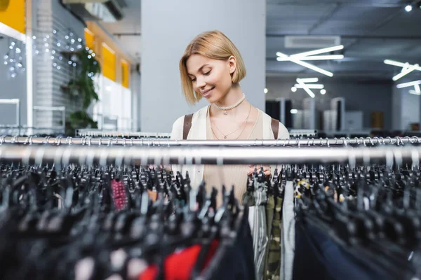 Позитивная женщина выбирает одежду в магазине ретро — стоковое фото