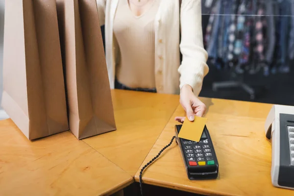 Vista recortada de la mujer que paga con tarjeta de crédito cerca de bolsas de compras en segunda mano - foto de stock